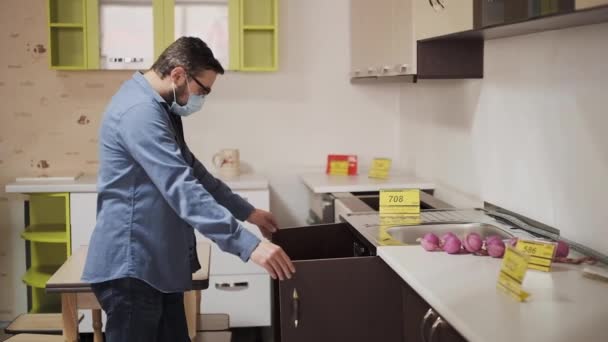 Клиент в защитной маске выбирает мебель для кухни — стоковое видео