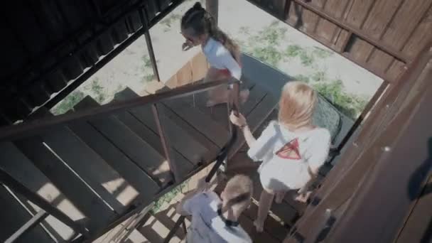 Радостная семья поднимается по деревянной лестнице держа черные перила — стоковое видео