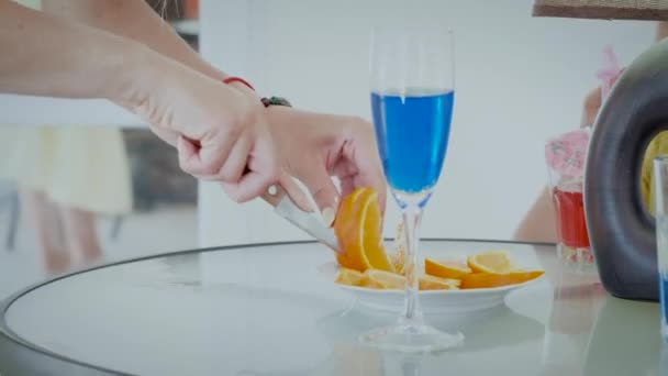 Frauenhände schneiden Orangen auf dem Tisch zwischen Getränken in Großaufnahme — Stockvideo