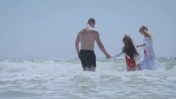 Lang haar meisje in rood badpak springt in zwaaien oceaan — Stockvideo