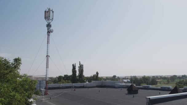 Une tour cellulaire installée sur le toit d'un bâtiment dans une zone rurale. — Video