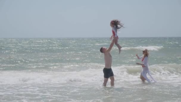 Hombre lanza hija de pie en el océano sin fin aguas poco profundas — Vídeo de stock