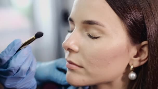 Cosmetologist in gloves applies eyeshadows on client face — Stock Video