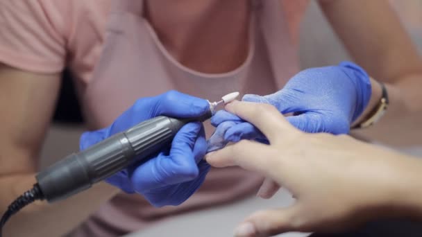 Manikúra mistr v modrých rukavicích leští klientovi nehty v salonu — Stock video