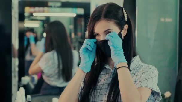 Kosmetikerin in Latexhandschuhen setzt Schutzmaske im Salon auf — Stockvideo