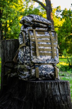 Yaz ormanlarında yürüyüş ve eski ağaç kütüğünde seyahat için yeni kamuflaj çantası. Yakın plan.
