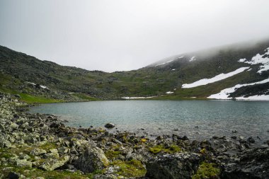 Bulutlu bir günde dağ sırasının önünde dağ gölü olan güzel panoramik manzara, Rusya 'nın çevresel Ural dağları,
