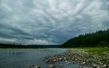 Dağlık Kozhim nehri üzerinde ağır bulutlar ve kozalaklı orman, Ural dağları, Rusya