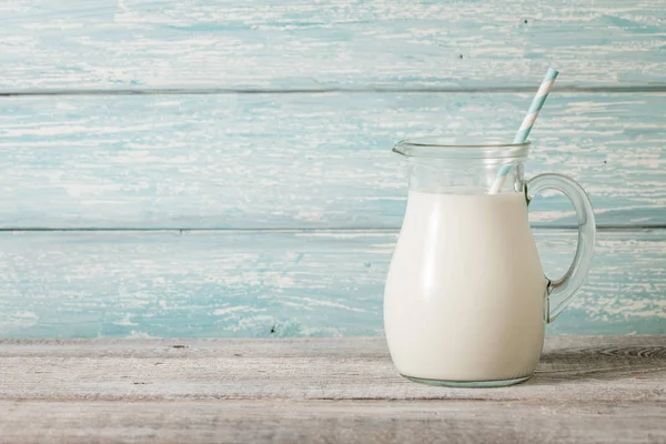 Glass pitcher with milk on wooden table