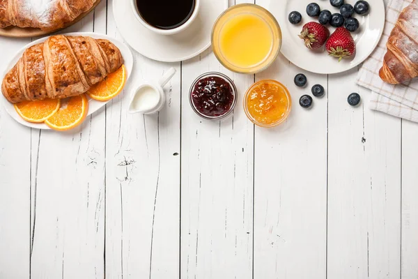 Desayuno con cruasanes, café, zumo de naranja, fruta y berr —  Fotos de Stock