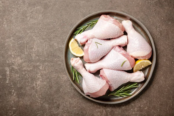 Свежие сырые куриные ножки с розмарином и лимоном для приготовления пищи — стоковое фото