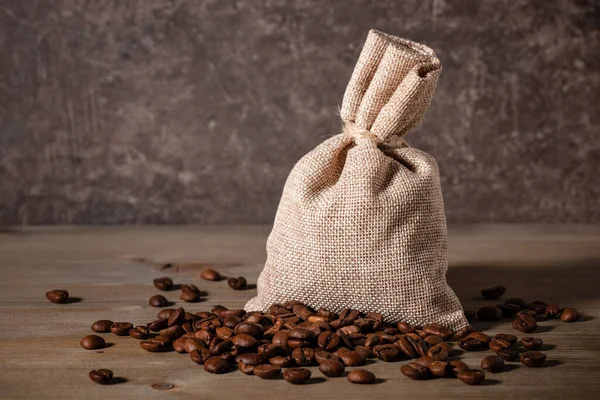 Coffee beans in bag and on wooden table