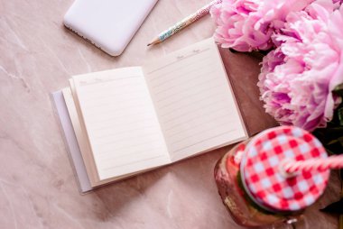 Güzellik düz bir günlük, smartphone, aksesuarları ve peonies mermer bir zemin üzerine yatırın. Üstten görünüm