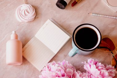 Güzellik düz bir günlüğü, fincan kahve, aksesuarları ve peonies mermer zemin ile yatıyordu. Üstten görünüm