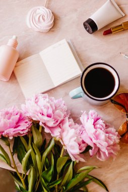 Güzellik düz bir günlüğü, fincan kahve, aksesuarları ve peonies mermer zemin ile yatıyordu. Üstten görünüm