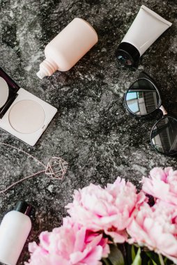Güzellik düz aksesuarları, parfüm, kozmetik ve peonies karanlık mermer zemin üzerine yatırın. Üstten görünüm
