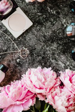 Güzellik düz aksesuarları, parfüm, kozmetik ve peonies karanlık mermer zemin üzerine yatırın. Üstten görünüm