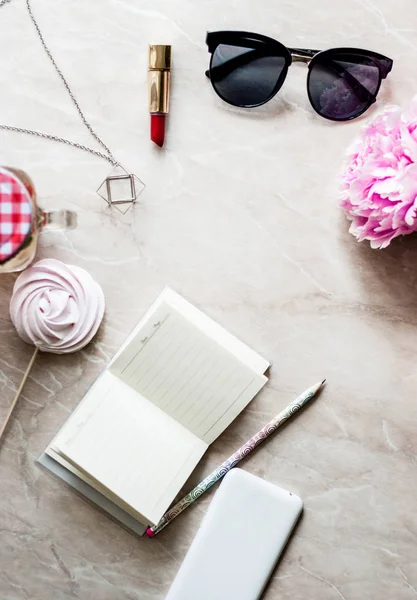 Güzellik düz bir günlük, smartphone, aksesuarları ve peonies mermer bir zemin üzerine yatırın. Üstten görünüm