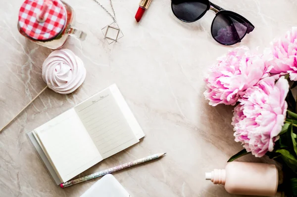 Güzellik düz bir günlük, smartphone, aksesuarları ve peonies mermer bir zemin üzerine yatırın. Üstten görünüm