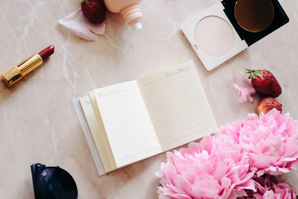 Güzellik düz bir günlük, smartphone, aksesuarları ve peonies mermer bir zemin üzerine yatırın. Üstten görünüm