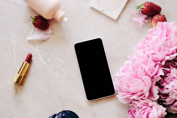 Güzellik düz bir günlük, smartphone, aksesuarları ve peonies mermer bir zemin üzerine yatırın. Üstten görünüm