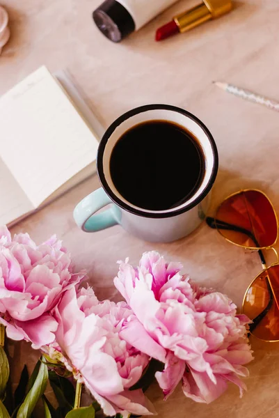 Güzellik düz bir günlüğü, fincan kahve, aksesuarları ve peonies mermer zemin ile yatıyordu. Üstten görünüm