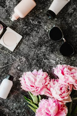Güzellik düz aksesuarları, parfüm, kozmetik ve peonies karanlık mermer zemin üzerine yatırın. Üstten görünüm