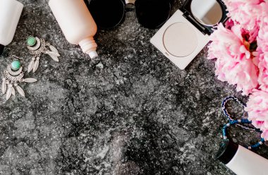 Güzellik düz aksesuarları, parfüm, kozmetik ve peonies karanlık mermer zemin üzerine yatırın. Üstten görünüm