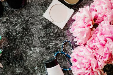 Güzellik düz aksesuarları, parfüm, kozmetik ve peonies karanlık mermer zemin üzerine yatırın. Üstten görünüm