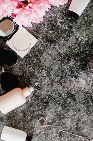 Güzellik düz aksesuarları, parfüm, kozmetik ve peonies karanlık mermer zemin üzerine yatırın. Üstten görünüm