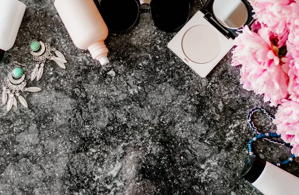 Güzellik düz aksesuarları, parfüm, kozmetik ve peonies karanlık mermer zemin üzerine yatırın. Üstten görünüm
