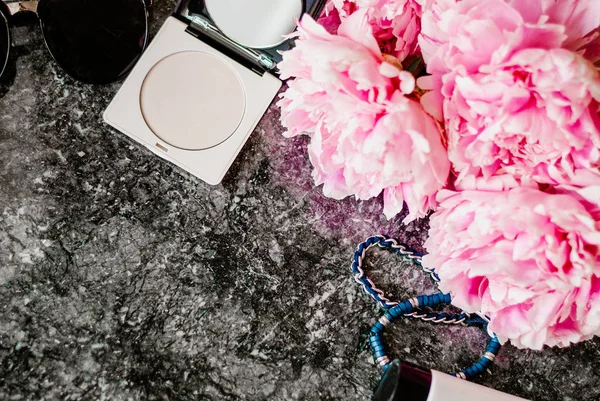 Güzellik düz aksesuarları, parfüm, kozmetik ve peonies karanlık mermer zemin üzerine yatırın. Üstten görünüm