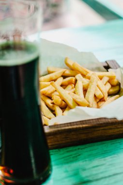 Patates kızartması bir ahşap tahta ve karanlık bira. Sağlıksız yiyecek