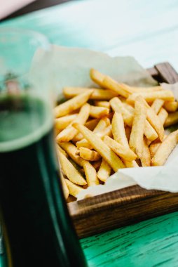 Patates kızartması bir ahşap tahta ve karanlık bira. Sağlıksız yiyecek