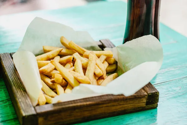 Patates kızartması bir ahşap tahta ve karanlık bira. Sağlıksız yiyecek