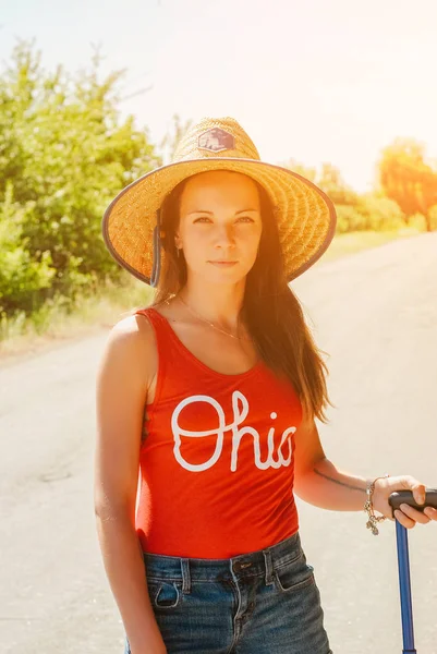 güzel ve çekici kadın çanta ülke Road, hasır şapkalı kameraya benziyor