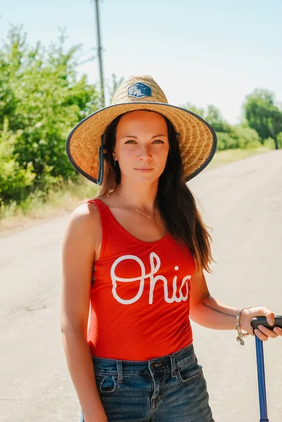 güzel ve çekici kadın çanta ülke Road, hasır şapkalı kameraya benziyor