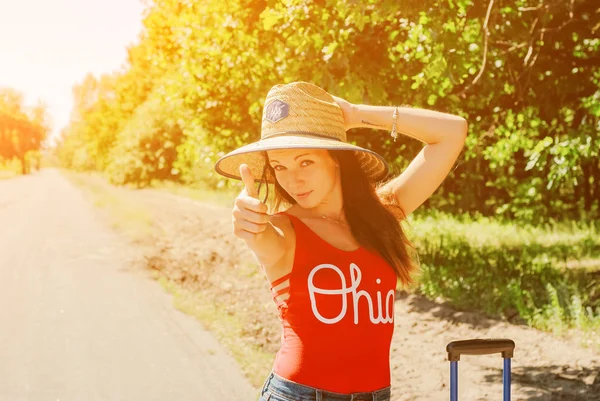 Kadın bir hasır şapka ve kırmızı gömlek gülümseyen kadar yaşasın vererek hiking. Kamera yürüyüş gezisinde açık, neşeli gülümseyen kadın uzun yürüyüşe çıkan kimse