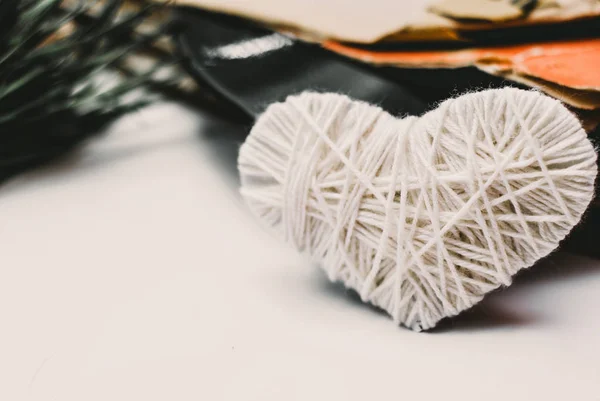 white knitted heart and stack of scratched dusty old vinyl records tied with rope on white background