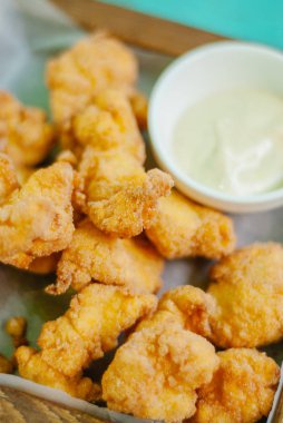 Ahşap tahtada soslu kızarmış tavuk nugget.