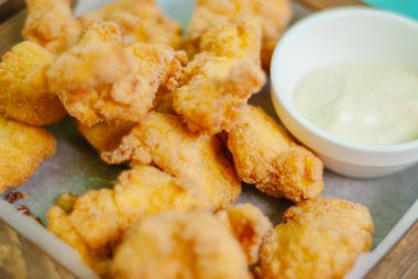 Ahşap tahtada soslu kızarmış tavuk nugget.