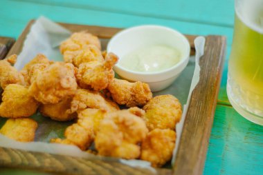 Ahşap tahtada soslu kızarmış tavuk nugget.