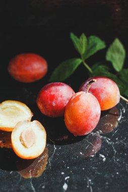 yeşil yaprakları ile siyah bir zemin üzerine taze Erik