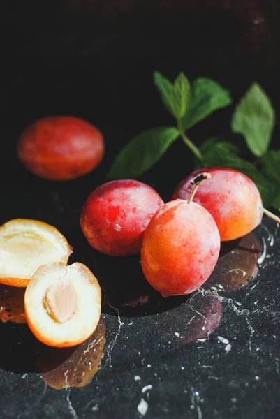 yeşil yaprakları ile siyah bir zemin üzerine taze Erik