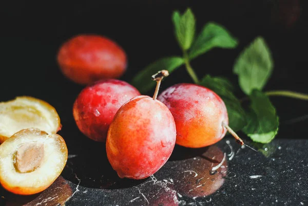 yeşil yaprakları ile siyah bir zemin üzerine taze Erik