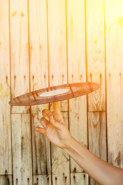 Female hand holding vinyl record over wooden background