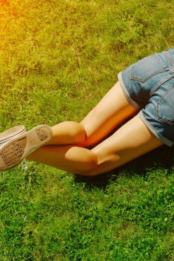 Genç kadın bir güneşli yaz günde çim yalan. Bacaklar.