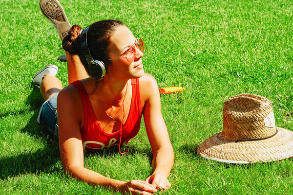 молодая брюнетка женщина слушает музыку на открытом воздухе в летний день
