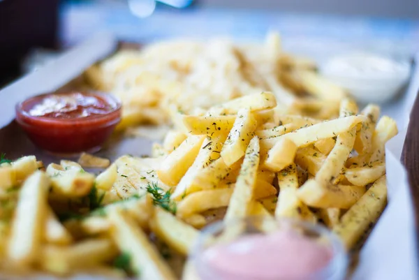 French fries with spicy seasoning in wooden plate on wooden broad. — Stock Photo, Image