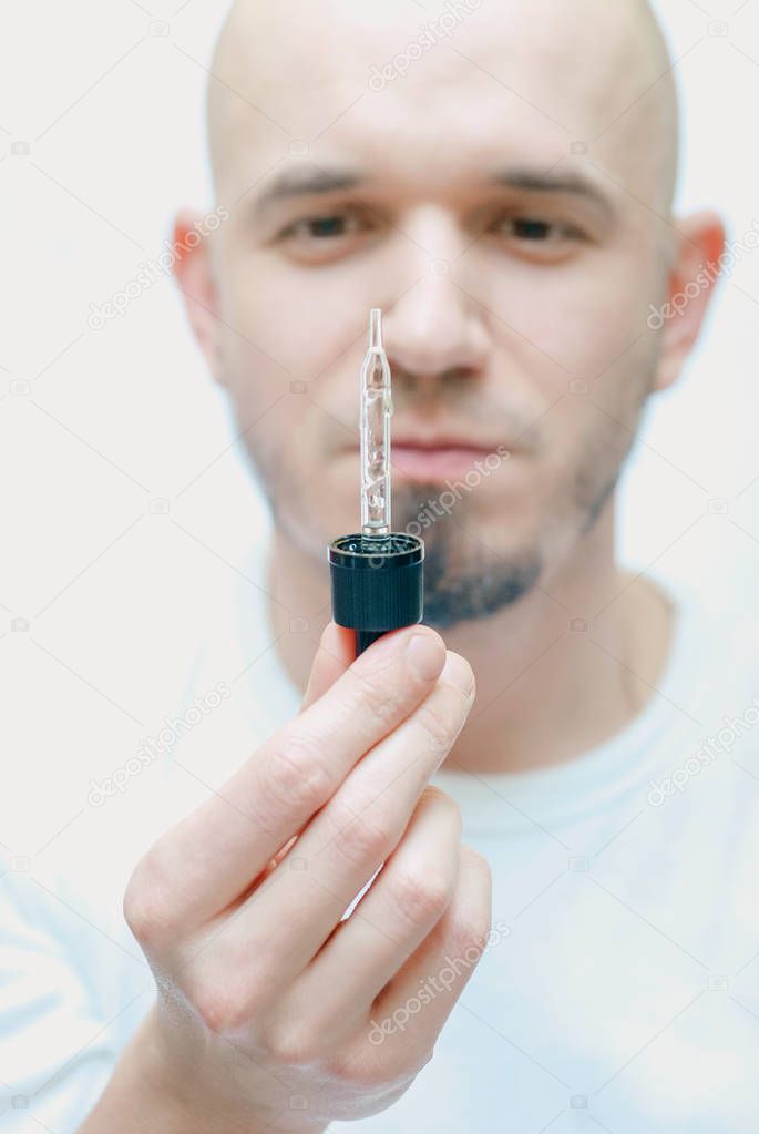 handsome man with pipette with beard oil